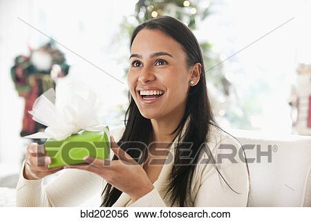 Stock Photograph - Hispanic woman holding Christmas gift. Fotosearch