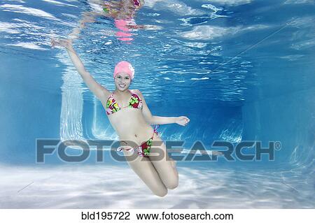 Stock Image - Hispanic woman in bikini swimming underwater. Fotosearch