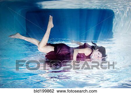 Stock Image - Hispanic woman in dress laying on top of water. Fotosearch
