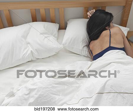 Stock Photo - Hispanic woman laying in bed. Fotosearch