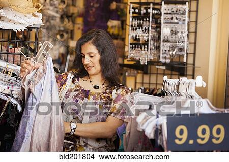 Picture - Hispanic woman shopping in clothing store. Fotosearch