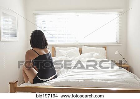 Hispanic woman sitting on bed View Large Photo Image Picture - Hispanic woman sitting on bed. Fotosearch