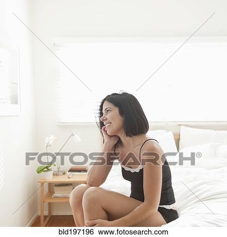 Hispanic woman sitting on bed talking on cell phone View Large Photo Image Stock Photograph - Hispanic woman sitting on bed talking on cell phone. Fotosearch