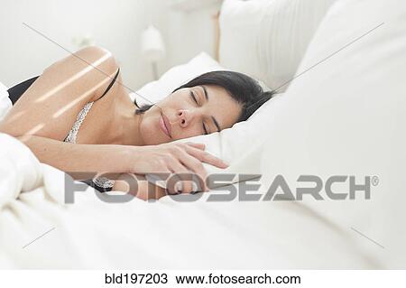 Stock Image - Hispanic woman sleeping in bed. Fotosearch