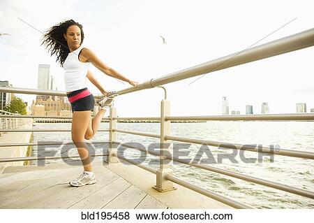 Hispanic woman stretching against railing at waterfront View Large Photo Image Stock Photo - Hispanic woman stretching against railing at waterfront. Fotosearch