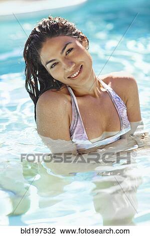 Stock Image - Hispanic woman swimming in swimming pool. Fotosearch