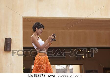 Stock Image - Hispanic woman using digital camera. Fotosearch