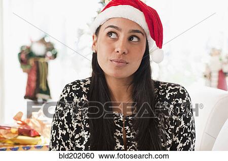 Stock Image - Hispanic woman wearing Santa hat. Fotosearch