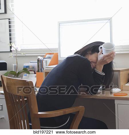 Stock Image - Hispanic woman working in home office drinking coffee. Fotosearch