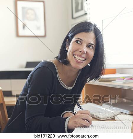 Stock Image - Hispanic woman working in home office. Fotosearch