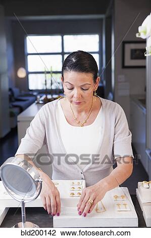 Stock Image - Hispanic woman working in jewelry store. Fotosearch