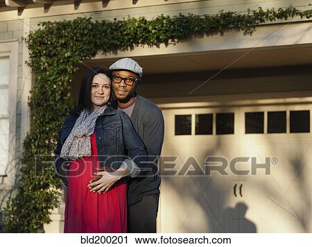 Stock Image - Husband hugging pregnant wife outdoors. Fotosearch