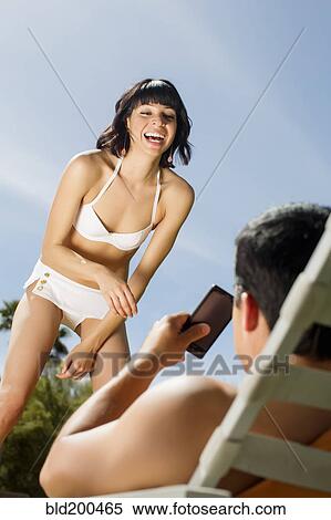 Stock Photography - Husband taking picture of wife with cell phone. Fotosearch