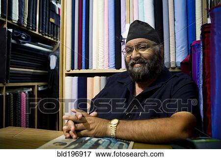 Stock Photo - Indian business owner sitting in fabric store. Fotosearch