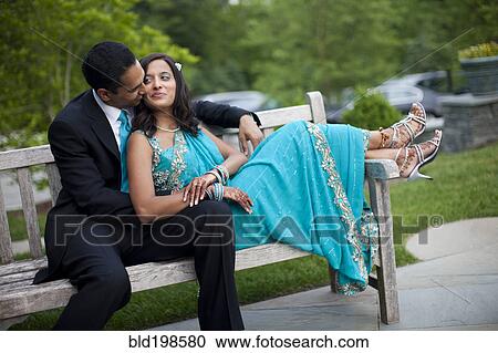 Stock Image - Indian man kissing wife in traditional clothing. Fotosearch