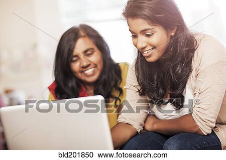 Stock Image - Indian mother and daughter using laptop together. Fotosearch