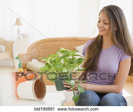 Stock Image - Indian woman putting house plant into pot. Fotosearch