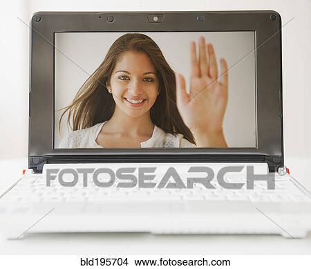 Picture - Indian woman waving from laptop display screen. Fotosearch