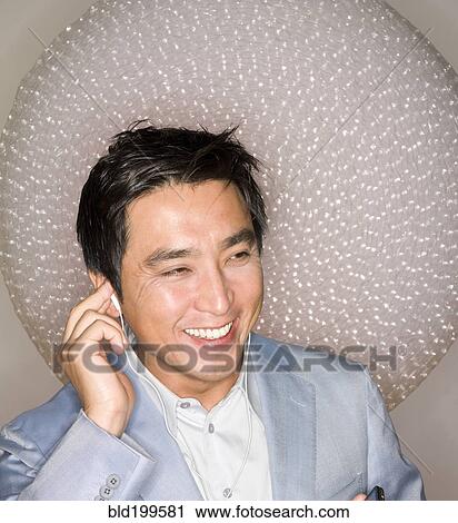 Stock Image - Japanese man listening to headphones. Fotosearch