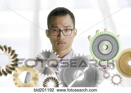 Stock Image - Korean man standing with gears. Fotosearch