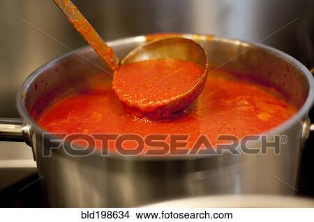 Picture - Ladle in pot of marinara sauce. Fotosearch