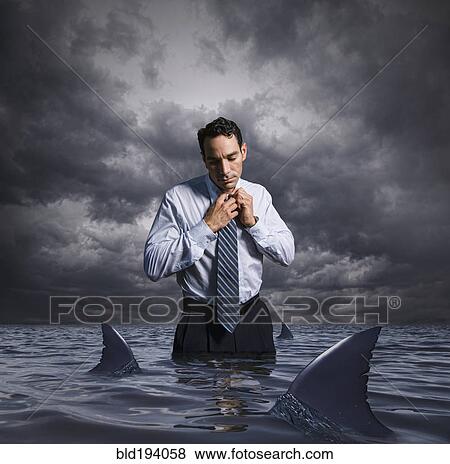 Latin businessman standing in shark infested waters View Large Photo Image Stock Photo - Latin businessman standing in shark infested waters. Fotosearch