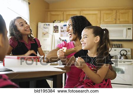 Picture - Laughing family sitting in kitchen. Fotosearch