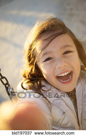 Stock Photo - Laughing mixed race girl swinging. Fotosearch