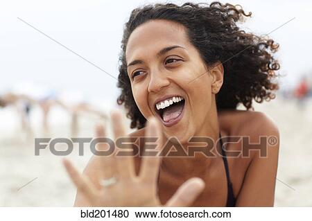 Stock Image - Laughing mixed race woman on beach. Fotosearch