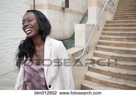 Stock Image - Laughing woman descending staircase. Fotosearch