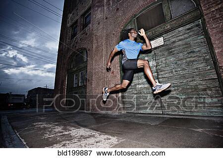 Stock Photo - Male athlete running on sidewalk. Fotosearch