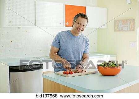 Man cutting vegetables in kitchen View Large Photo Image Stock Photo - Man cutting vegetables in kitchen. Fotosearch