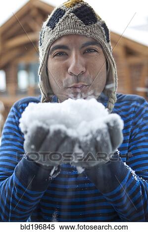 Stock Photography - Man in cap blowing snow. Fotosearch