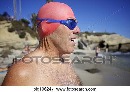 Stock Photo - Man in swim cap and goggles on beach. Fotosearch