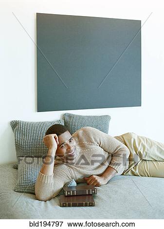 Stock Photo - Man laying on bed with books. Fotosearch
