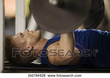 Stock Photo - Man lifting weights in health club. Fotosearch
