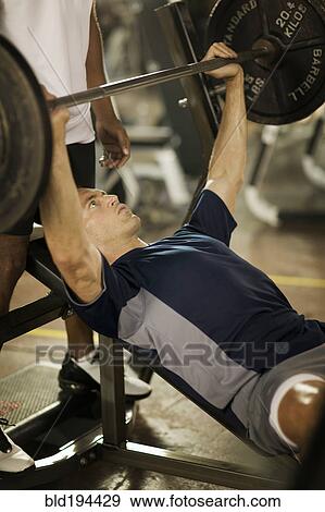 Stock Photo - Man lifting weights in health club. Fotosearch