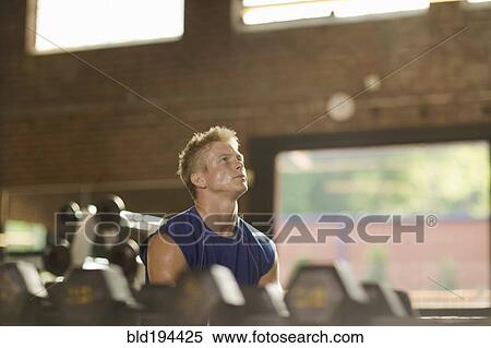 Stock Photography - Man lifting weights in health club. Fotosearch