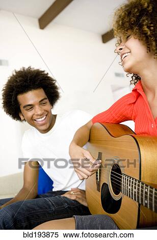 Stock Photography - Man listening to girlfriend play guitar. Fotosearch