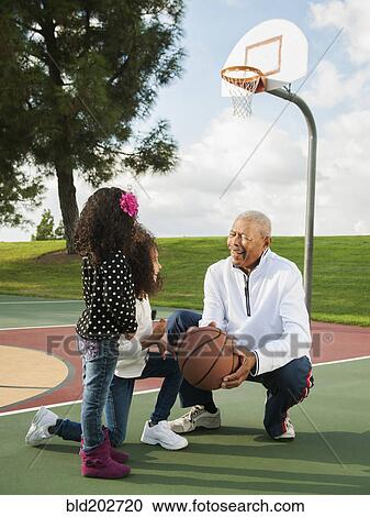 Stock Image - Man playing basketball with granddaughters. Fotosearch
