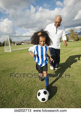Stock Image - Man playing soccer with granddaughter. Fotosearch