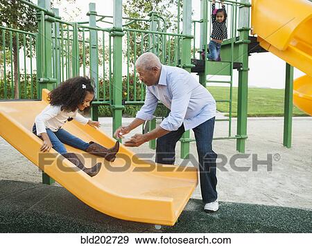Stock Photo - Man playing with granddaughter at park. Fotosearch