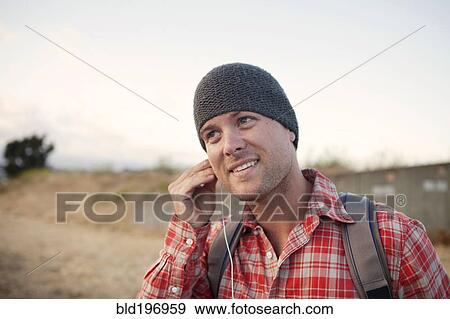 Stock Photo - Man putting in earbuds in remote area. Fotosearch