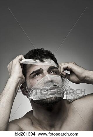 Picture - Man removing bandage from his face. Fotosearch