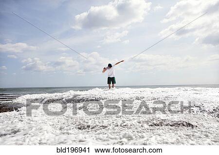 Stock Image - Man standing in ocean waves. Fotosearch