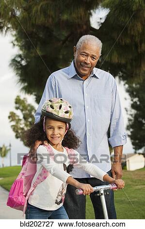 Stock Photo - Man standing with granddaughter outdoors. Fotosearch