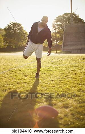 Stock Image - Man stretching on football field. Fotosearch