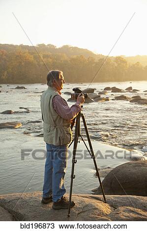 Stock Image - Man taking photographs on beach. Fotosearch