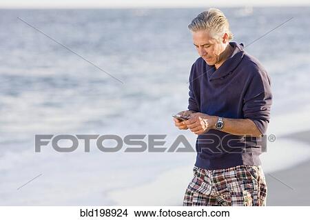 Man using cell phone on beach View Large Photo Image Picture - Man using cell phone on beach. Fotosearch