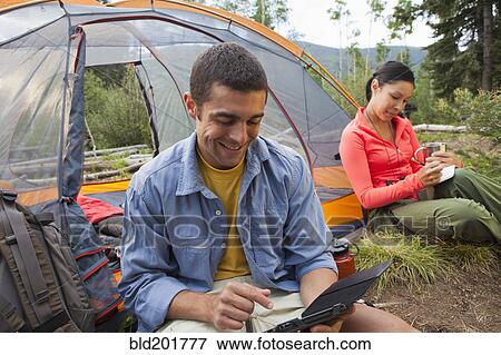 Man using digital tablet while camping View Large Photo Image Stock Photo - Man using digital tablet while camping. Fotosearch